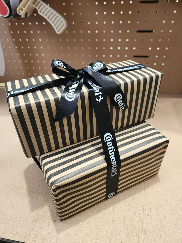 A striped gift box tied with Continental ribbon on the packing bench