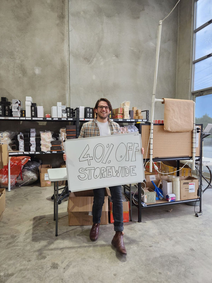 Thomas holding the 40 percent off storewide whiteboard, November 2024